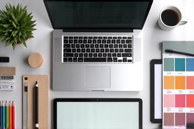 Creative workspace with a laptop, tablet, and graphic design tools